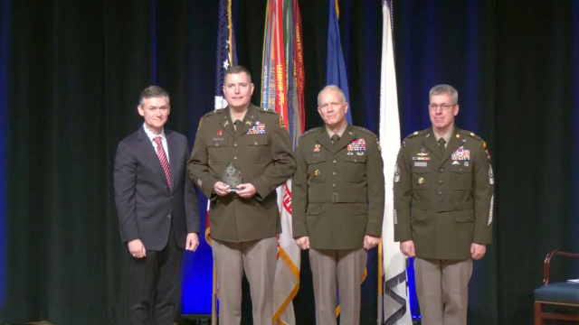 Col. Chris Anderson, Project Manager Intelligence Systems & Analytics, center left, smiles holding his team's trophy for 2024 Army Acquisition O-6 Project Manager Team of the Year award with Hon. Douglas Bush, Assistant Secretary of the Army for Acquisition, Logistics and Technology, left; Lt. Gen. Robert Collins, Military Deputy for ASA(ALT), center right; and Sgt. Maj. Robert Haynie, at a ceremony Jan. 10. (Photo Credit: Courtesy photo)